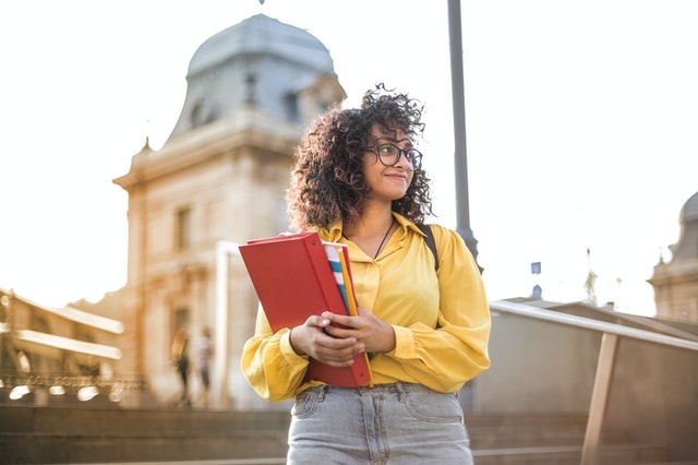 student carrying book on campus